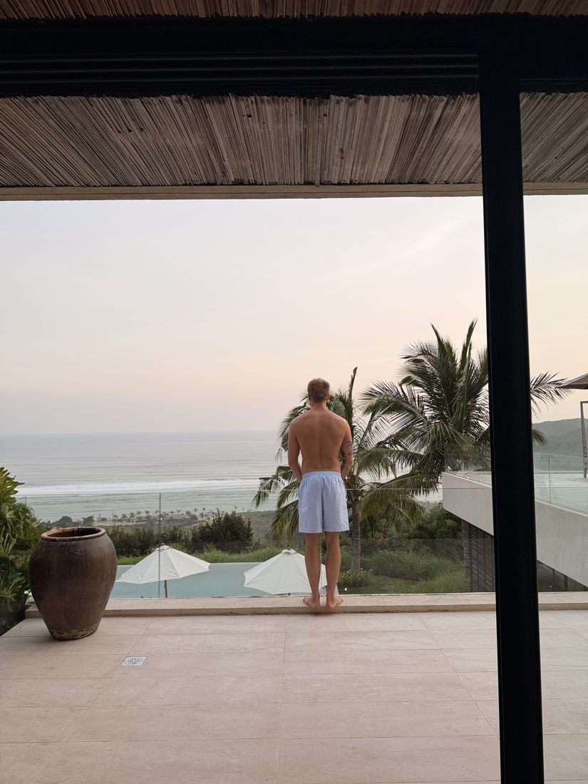 Mann ser utover havet fra terrassen på en villa i tropene