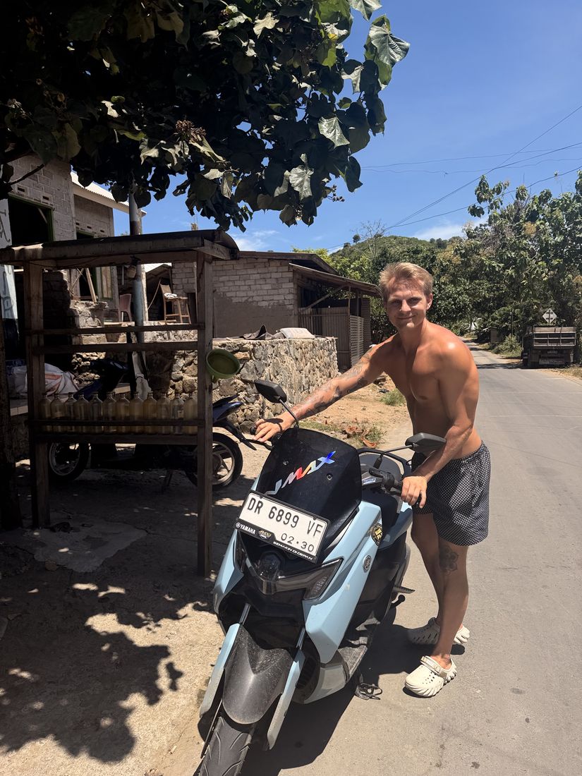 Smilende reisende med leid scooter på en landevei i Asia